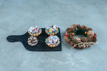 Fototapeta premium Cupcakes on a board next to a wreath on marble background