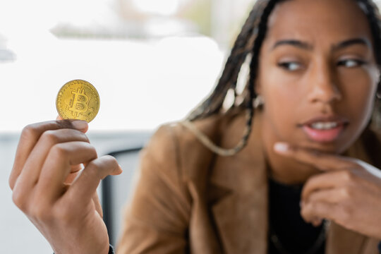 KYIV, UKRAINE - APRIL 27, 2022: Blurred african american businesswoman looking at bitcoin in office.