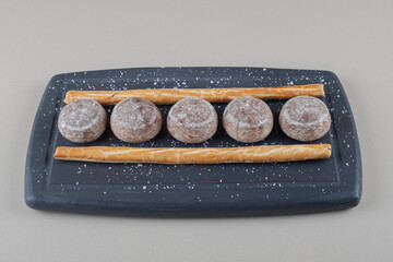 Small cookies and stick crackers on navy platter on marble background