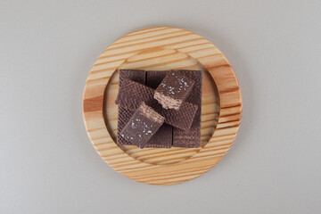 Chocolate wafers bundled together on a wooden platter on marble background