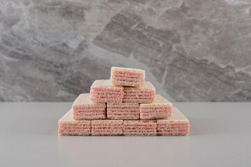 Stack of wafers with strawberry cream filling on marble background