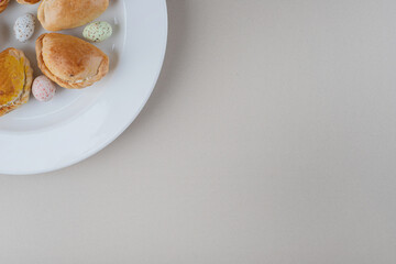 Small buns and candy rocks on a platter on marble background