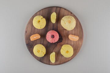 Arrangement of marmelades and cookies on a wooden board on marble background