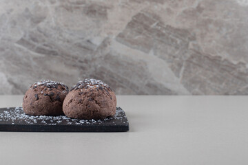 Chocolate topped cookies on a black board on marble background