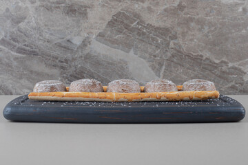 Small cookies and stick crackers on navy platter on marble background