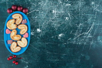 Tasty cookies with sugar jelly candy on a blue board