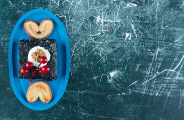 A blue board with a piece of chocolate cake and cookies