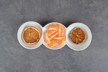 Dried tangerine slices and fresh segments in white bowls