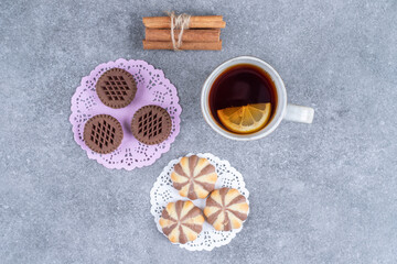 Assortment of sweets and cup of tea on marble background