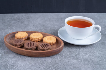 Oat and cocoa biscuits with cup of tea on marble surface