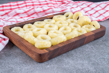 Tasty circle crackers on wooden plate with tablecloth