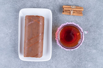 Chocolate roll cake and hot tea on marble surface