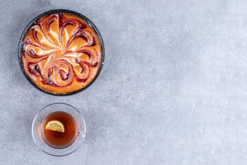 Delicious pie with berry and cup of tea on marble background
