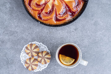 Delicious pie with berry, biscuits and cup of tea on marble background