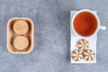 Cup of black tea with various biscuits on marble background