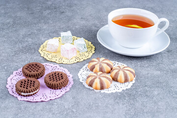 Assortments of sweets and cup of tea on marble surface
