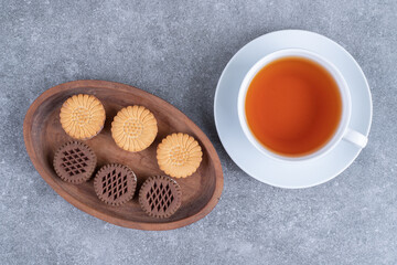 Oat and cocoa biscuits with cup of tea on marble surface