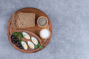A wooden cutting board with boiled egg and slices of bread