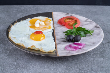 A plate with fried eggs and sliced vegetables