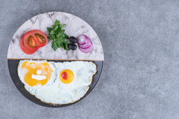 A plate with fried eggs and sliced vegetables