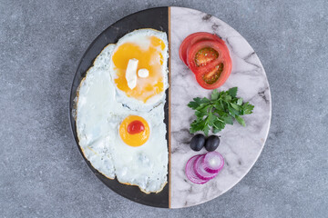 A plate with fried eggs and sliced vegetables