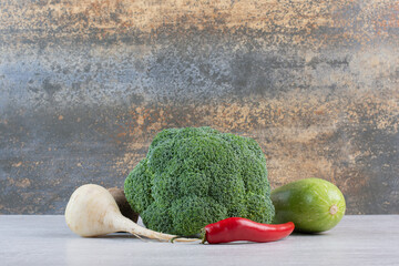 White turnip, broccoli and chili pepper on stone surface