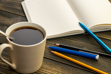 mug of coffee on the table next to the diary with a pen and pencil in the morning