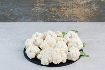 Sliced fresh cauliflower with leaves on black board