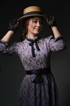 A girl in a blue retro dress in the style of the 1900s. A woman adjusts her hat in lace gloves. Historical fashion of the 19th century. High quality photo