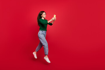 Full size photo of cute energetic girl rejoice message follower comment dressed stylish green outfit isolated on bright red color background