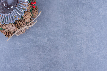 A glass plate with a chocolate cake and pinecones