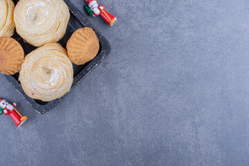 Tasty pastries with Christmas toys on a gray background