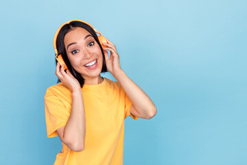 Photo of positive pretty person hands touch headphones empty space isolated on blue color background