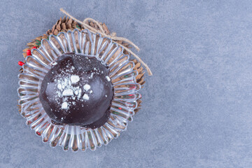 A chocolate cake with pinecones on a glass plate