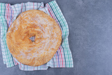 A round delicious pastry with sugar powder on a tablecloth