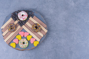 A dark plate full of donuts and heart shaped jelly candies