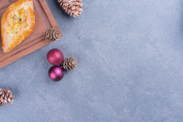 Delicious pastry with Christmas balls on a wooden board
