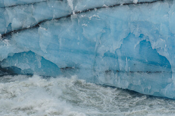 texture and background of glacier ice walls crossed by black lines of land. © Juan