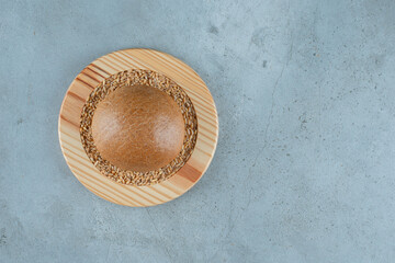Fragrant rye bun on wooden plate with barley