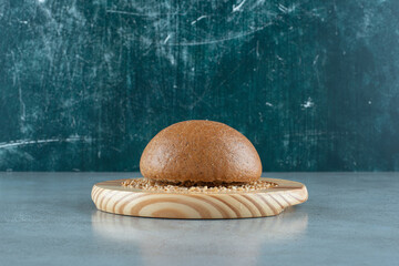 Fragrant rye bun on wooden plate with barley