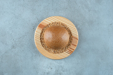 Fragrant rye bun on wooden plate with barley