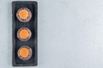 Marmelades and a chocolate chip cookies stacked on a tray on marble background