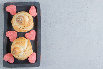 Buns with sesame seeds and marmelades on a black tray on marble background