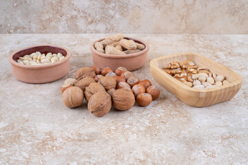 Bowls of hazelnuts, peanuts, sunflower seeds and popcorn on marble surface