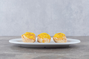 Three small buns on a platter on marble background