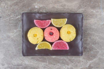 Colorful cookies and marmelades bundled on a platter on marble background