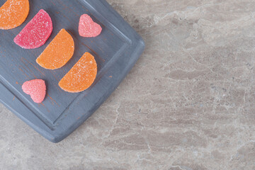 Marmelades neatly arranged on a navy board on marble background