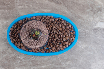 Chocolate cake on a platter full of coffee beans on marble background