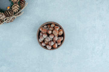Pine cone wreath and bowl fo hazelnuts on marble background