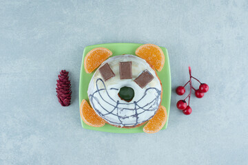 Small plate with donut and marmelades next to christmas ornaments on marble background